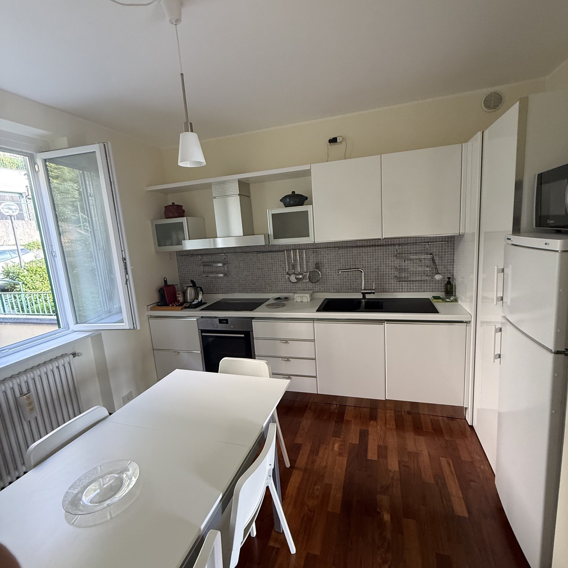 Equipped white kitchen with oven, hob, microwave and dining table